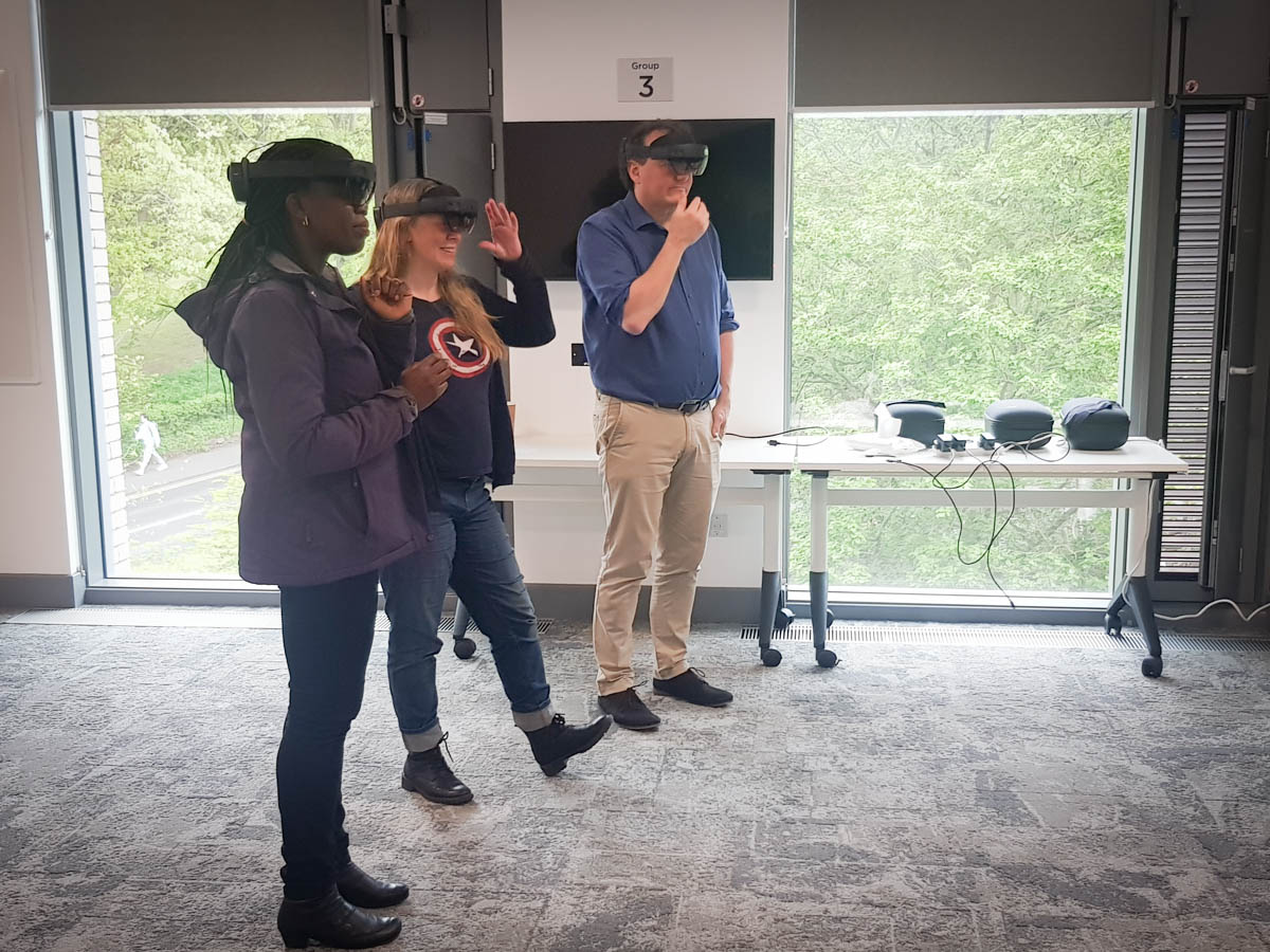 Three people stood in a room all wearing Microsoft HoloLens headsets.